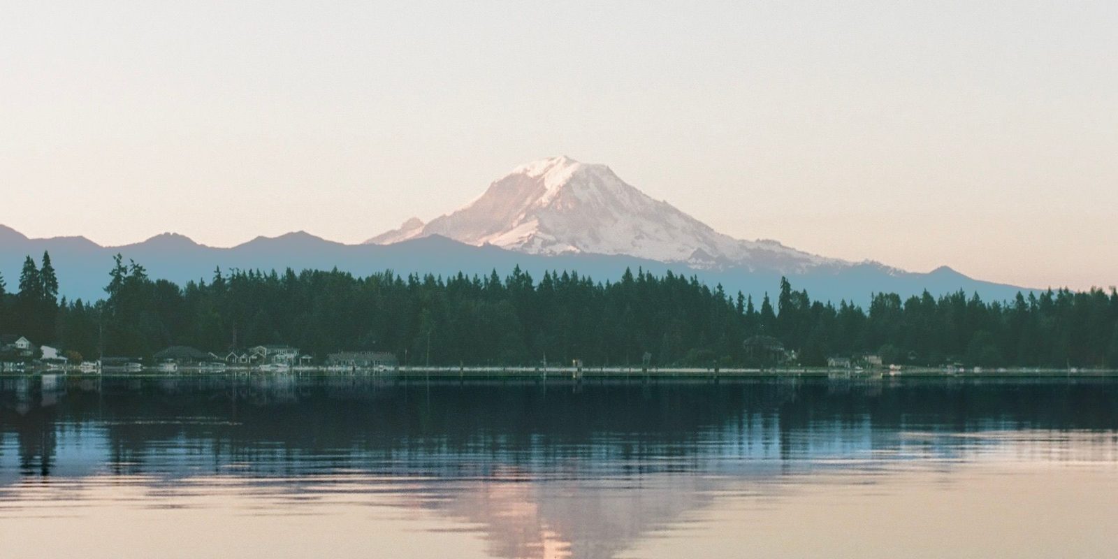 Mount Rainier at dusk above a Douglas fir shoreline reflected in a still Snohomish County lake