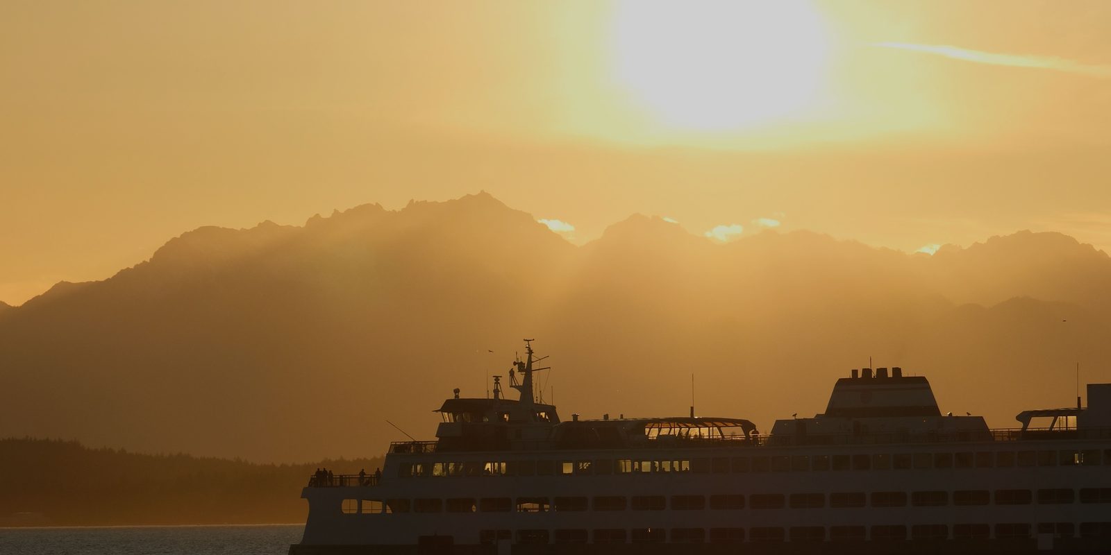 The Olympic Mountains at sunset behind a Washington State ferry crossing Puget Sound