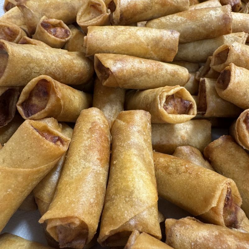 Many tightly rolled, golden brown lumpia fresh from the fryer, stacked every which way.