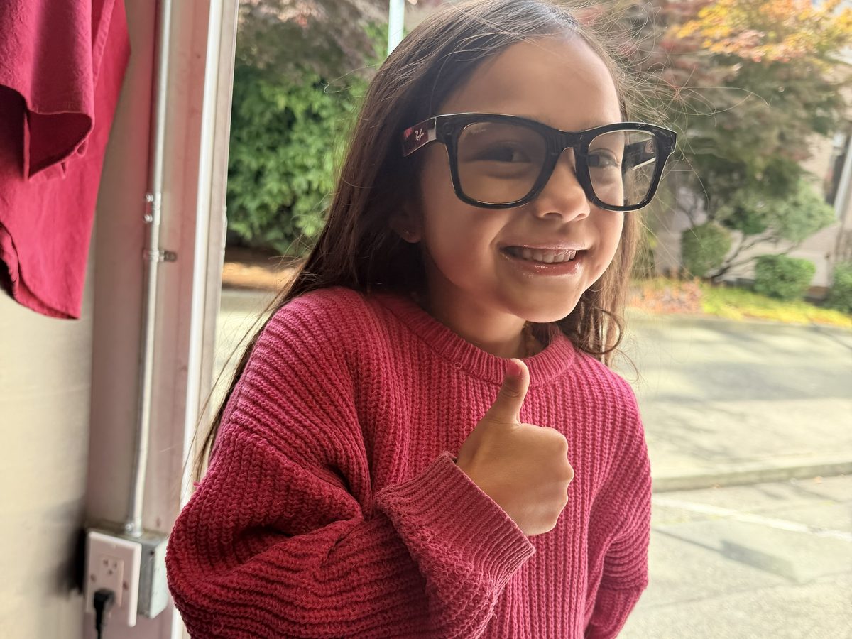 Chef Sarah’s youngest daughter standing in the doorway of the Fil Up! trailer in a red sweater and glasses. She is grinning and giving a thumbs up